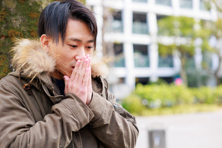 young asian man coughing and sneezing in the street.の写真素材