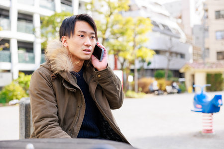 Man talking on the phone in the street. Asian male model.の写真素材
