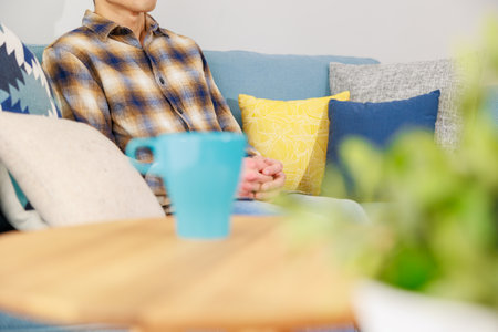 Close-up of woman sitting on sofa and reading book at homeの写真素材