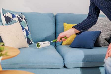 Close-up of woman using digital thermometer on sofa at homeの写真素材