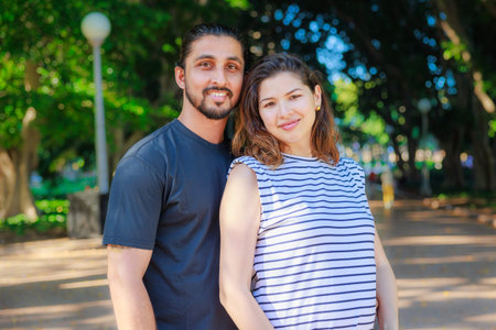 Portrait of a happy pregnant couple standing in the park and smiling