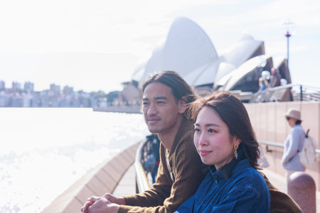 young happy and beautiful Asian couple in love enjoying holidays travel and honeymoon trip at famous Opera House in Sydney Australia having fun on winter holidaysの写真素材