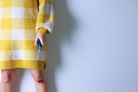 Girl in a yellow sweater with a thermometer in her hand.