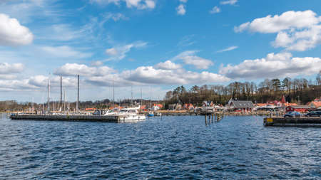 Mariager, Denmark - 29 march 2020: Scene from a Danish marina with view past yacht to houses by the coast, Mariagerのeditorial素材