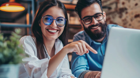 Beautiful young couple is using a laptop and smiling while working in cafeの素材