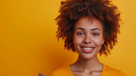 Portrait of a beautiful young african american woman with afro hairstyle on yellow backgroundの素材
