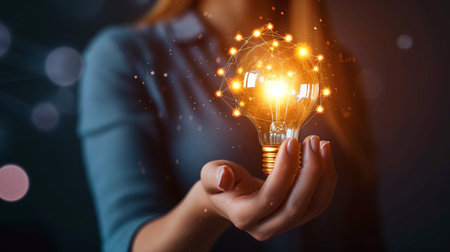 Close up of businesswoman holding lightbulb with circuit on itの素材