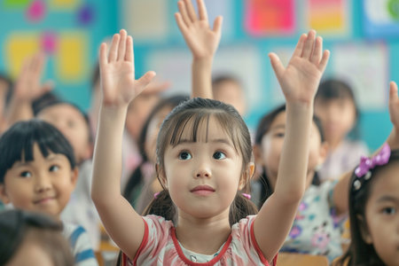 Cute asian little girl raising her hands in the classroom.の素材