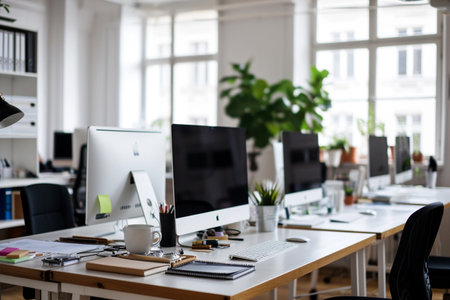 Office workplace with computers and other stuff on the table. blurred backgroundの素材
