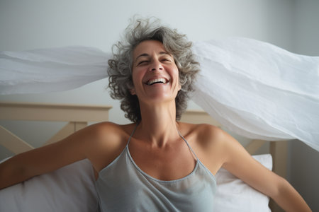 Portrait of a happy mature woman smiling while lying on bed at homeの素材