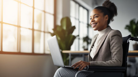Smiling african american businesswoman working on laptop in officeの素材