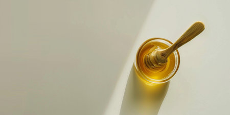 Honey in a jar with wooden spoon on a white background.の素材