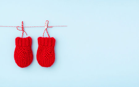 Red knitted mittens hanging on a rope on a blue backgroundの写真素材