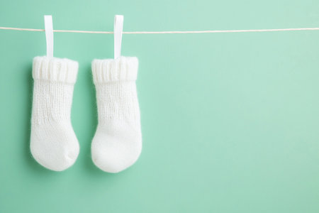 White baby socks hanging on clothesline on aquamarine background with copy spaceの写真素材