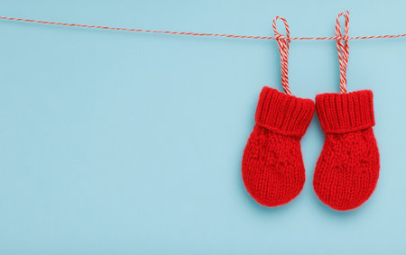 Red knitted mittens hanging on a rope on a blue backgroundの写真素材