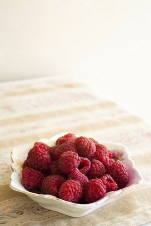 Bowl of Raspberries on flowered Fabricの写真素材