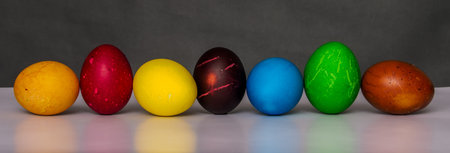Easter eggs painted in different colors with custom patterns, lined up in a row on a gradient...