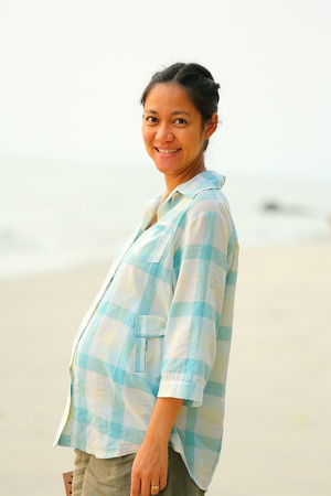 Pregnant woman smiles on the beach sideの写真素材