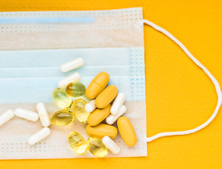 Close-up of white and yellow pills on  medical mask. intence yellow paper background. still life