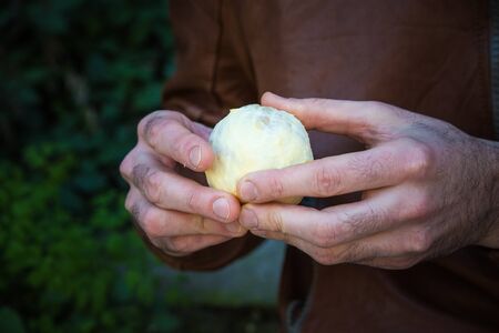 man holds in hands peeled round orange fruitの写真素材