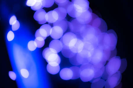 Abstract blur background in blue, white and violet color on black. defocused glittering lights in the darkness. Night magic of new year eve. Marry Christmas concept. Artistic glittering effect pattern design for backdrop or wallpaper. High quality photoの写真素材