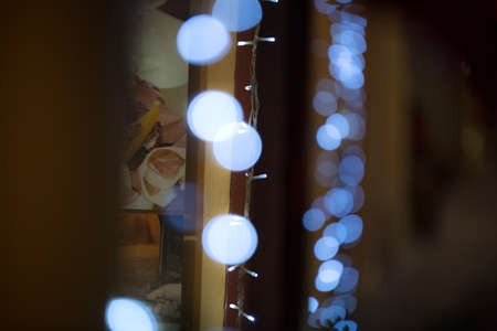 Abstract blur background with white bokeh behind in front of window. defocused glitter lights in darkness. Night magic of new year. LED illumination. Artistic pattern design for backdrop or wallpaper.の写真素材