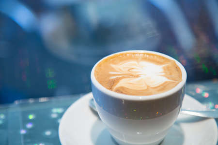 white cup of cappuccino with grey stripe and bokeh in background. Butterfly designed with milk foam on coffee. sparking confetti on the table. Isolation contest. Empty bar and social distanceの写真素材