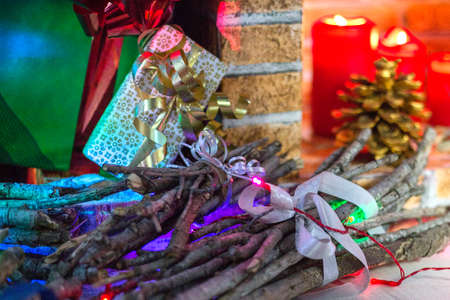Christmas composition at home. Fireplace, packed present boxes, branches and brushwood with new year lights garland. Postcard picture. Paper fireplace. Winter holidays home design. Waiting for Santa Claus. High quality photoの写真素材