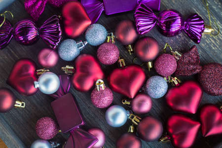 Many small red and silver decorations for Christmas tree. New year toys, hearts and balls on wooden grey surface. Flat layer composition for winter holiday card. Invitation background. Tender and love concept. . High quality photoの写真素材