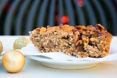 Golden Christmas ball and a piece of caramel cake with walnuts.の写真素材
