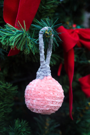 Knitted Christmas ball amigurumi on new year tree. Handmade plush Xmas decoration. Rose toy with grey top. Handycraftsの写真素材