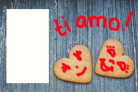 Ginger bread biscuits with fanny faces on grey wooden aged background with semi transparent copy space. Saint valentines frame with love declaration in italian. Ti amo. Invitation wallpaper. Togetherの写真素材