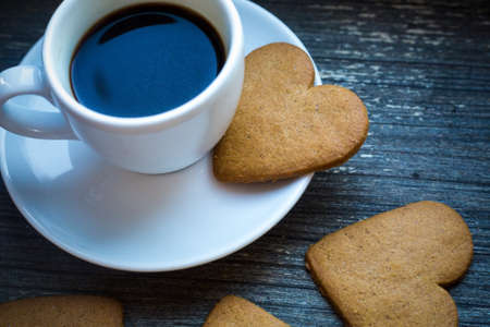 White coffeecup with hot fresh beverage and heart-shaped gingerbread biscuits. Coffee break with love. Side of coffee cup with hot beverage. Homemade sweets. Postcard and wallpaper picture. traditionの写真素材