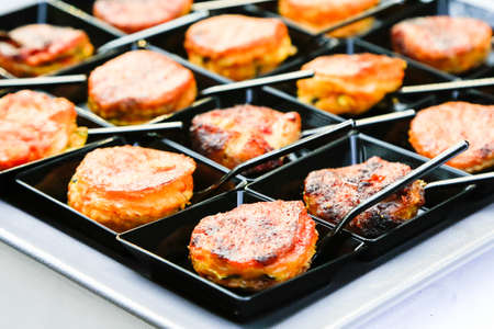 fingerfood closeup. small backed oriental snacks on square black plates with tiny spoons. Catering layout. Gourmet food degustation. Menu concept picture. Healthy dieting. corporate party snacksの写真素材