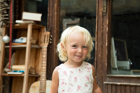 Little blond blue eye girl in white dress with pink flowers portrait. Tricky funny child. Retro...