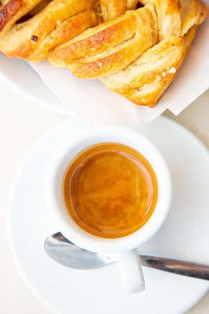 Top view to white cup of coffee ristretto and croissant. Traditional italian breakfast. Good morning concept. Daylight. Homemade bakery. Ginseng hot drink and apple pieの写真素材