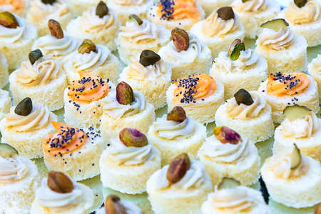 Small canapes with fish cream, pistachios and poppy seeds. Catering fingerfood for wedding. Diagonal composition. White bread based sandwiches. Gluten snacks. Delicious gourmet food degustationの写真素材