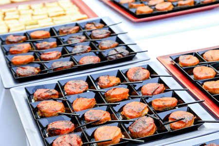 Catering fingerfood closeup. small backed oriental snacks on square black plates with tiny spoons. Gourmet food degustation. Menu concept picture. Healthy dieting. corporate party snacksの写真素材