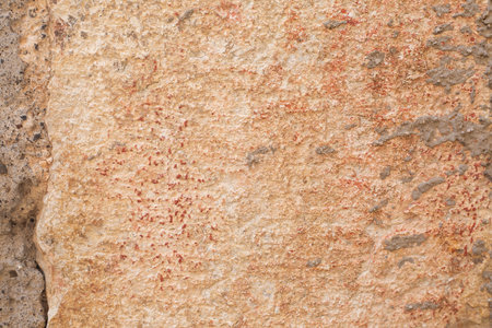 Beige and orange big stone block of wall with cement and red paint dots. Background and wallpaper...