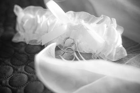 bridal garter for stockings with two silver hearts. Black and white monochrome picture. Wedding clothing element. Wallpaper picture. Love anniversary invitation. Preparation for partyの写真素材