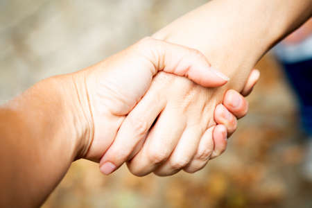 Diagonal composition. Two hands shaking outdoors. Team work and agreement setting. Women solidarity and support. Caucasian palm. Strength and collaboration. Greeting friends outdoors. Make businessの写真素材
