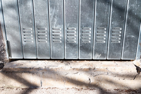 A long row of sturdy metal lockers is lined up neatly on a brick floor