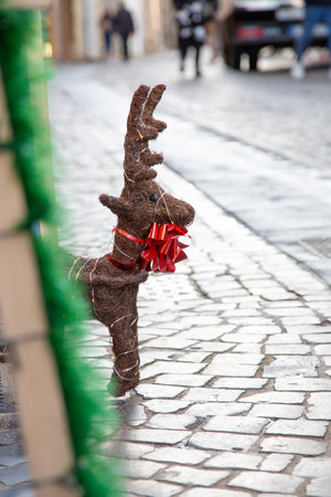 A stuffed reindeer with a red bow is sitting on the sidewalkの写真素材