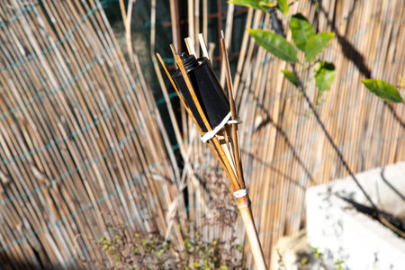 A beautifully crafted bamboo torch is positioned in front of a bamboo fenceの写真素材