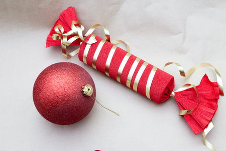 A red and gold striped candy placed beside a shiny red Christmas ballの写真素材