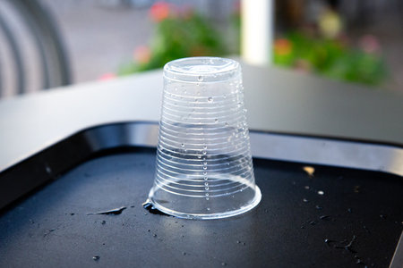 A plastic cup is currently sitting on a black tray placed on a tableの写真素材
