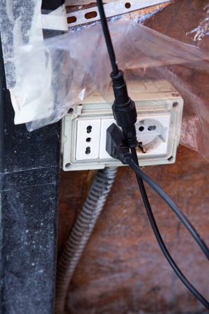 A black cord is currently plugged into a white electrical outletの写真素材