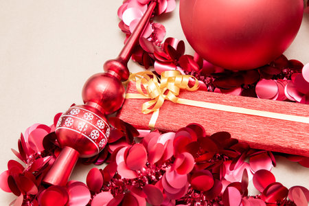 A bright, festive red Christmas ornament is perched atop a red gift boxの写真素材