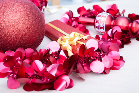 A vibrant red christmas ornament is beautifully surrounded by pink confettiの写真素材