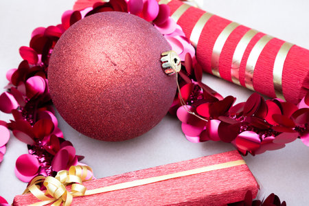 A red Christmas ball is surrounded by pink and gold decorationsの写真素材